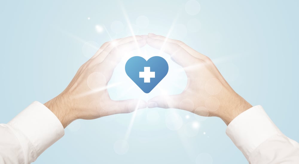 Hands creating a form with shining heart blue cross in the center